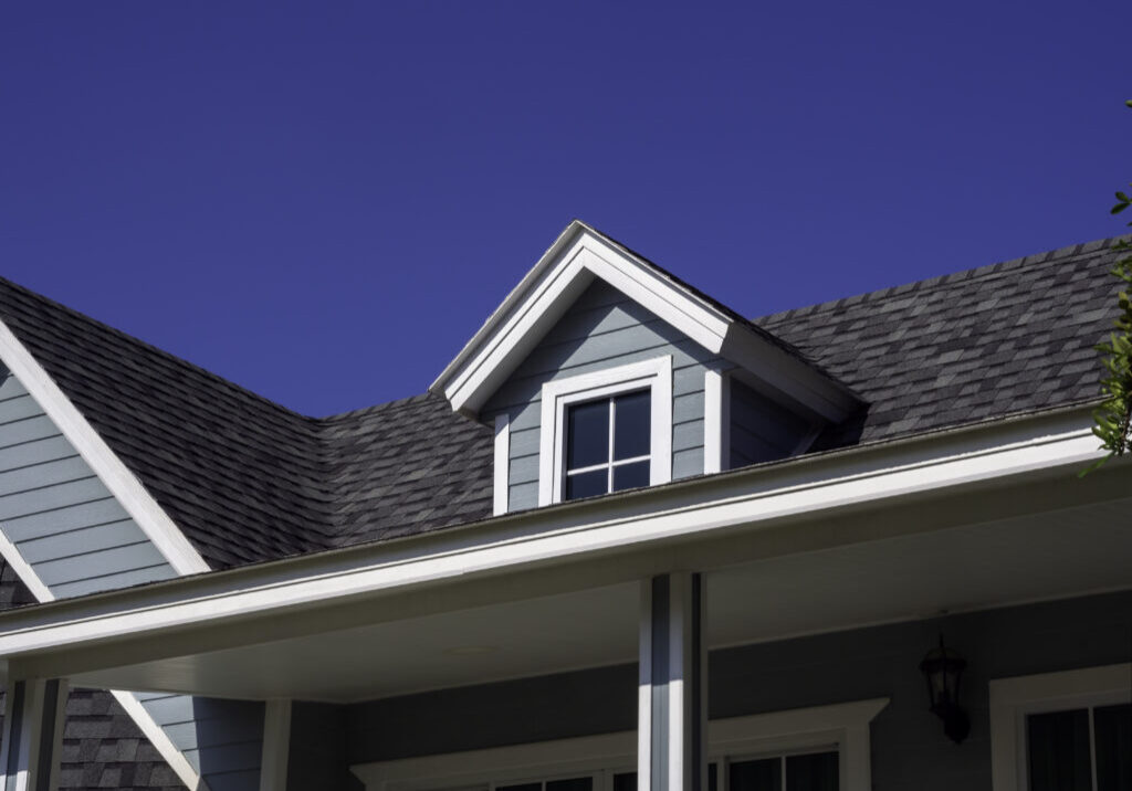 White vintage windows, little room decoration on the roof of the big wooden house pastel green color on blue sky background, view from outside.